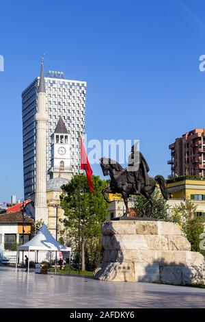 Der Hauptplatz von TiranaThe Et'Hem Bey Moschee, der Osmanischen Uhrturm, die modernen Hotels, die Nationalflagge und die Reiterstatue von skenderbeg Stockfoto