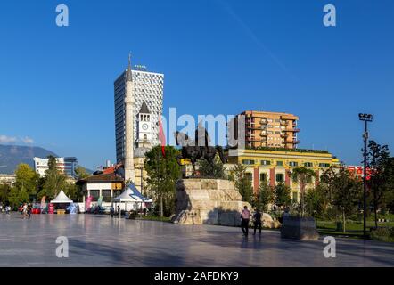 Der Hauptplatz von TiranaThe Et'Hem Bey Moschee, der Osmanischen Uhrturm, die modernen Hotels, die Nationalflagge und die Reiterstatue von skenderbeg Stockfoto