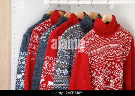 Verschiedene gestrickt Weihnachten rollkragen pullover oder Pullis mit Nordic geometrische Verzierung auf Kleiderbügel im Schrank Rack Stockfoto