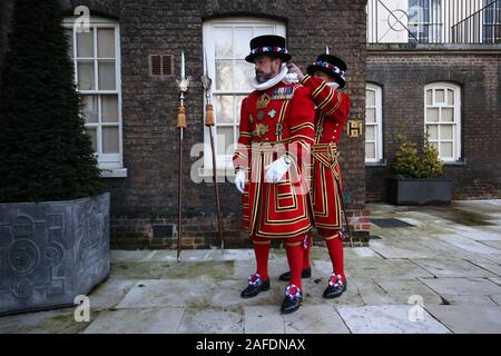 Yeoman Warder (besser bekannt als Beefeaters genannt) unterstützen sich gegenseitig mit ihren staatlichen Kleid vor Weihnachten State Parade am Tower von London. Stockfoto