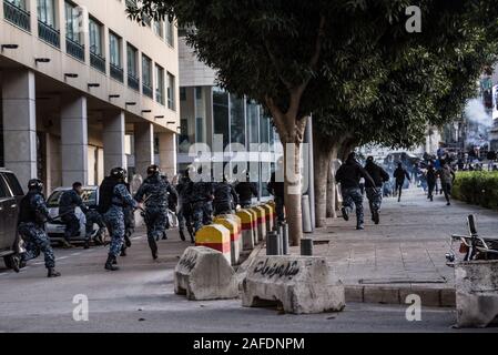 Beirut, Libanon. 14 Dez, 2019. Sicherheitskräfte Personal chase People Counter - Protest gegen eine libanesische Revolte gegen die Regierung durch die Straßen auf der 59. Tag des Protestes. Aus dem schiitischen Viertel Bachoura, in der Nähe der Innenstadt von Beirut, Zähler - Demonstranten griffen Polizei und Armee Personal mit Steinen und Feuerwerk am Samstagabend. Die Polizei antwortete mit Gas während einer warf Schlacht von mehreren Stunden. Credit: Elizabeth Fitt/Alamy leben Nachrichten Stockfoto