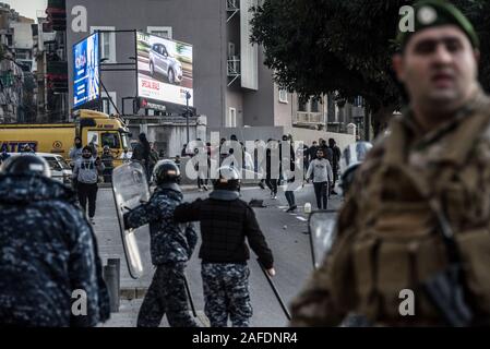 Beirut, Libanon. 14 Dez, 2019. Sicherheitskräfte personal Gesicht weg mit Menschen entgegen dem Protest gegen eine libanesische Regierung Revolte auf der 59. Tag des Protestes. Aus dem schiitischen Viertel Bachoura, in der Nähe der Innenstadt von Beirut, Zähler - Demonstranten griffen Polizei und Armee Personal mit Steinen und Feuerwerk am Samstagabend. Die Polizei antwortete mit Gas während einer warf Schlacht von mehreren Stunden. Credit: Elizabeth Fitt/Alamy leben Nachrichten Stockfoto