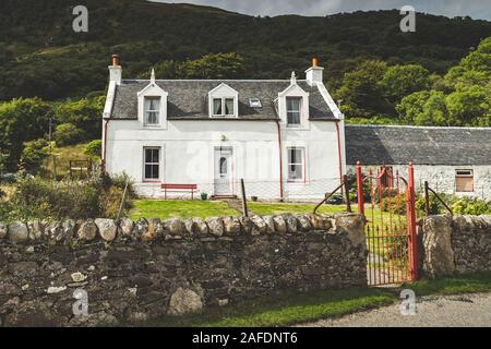 Traditionelle alte weiße Haus Nord Irland. Alte irische Cottage Gebäude mit Stone Fence und grüne Wälder Hügel im Hintergrund. Schöne Landschaft und Architektur Landschaft Foto Stockfoto