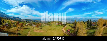 Antenne Panoramablick auf eine ländliche Region mit Bauernhöfen, Feldern und die Karpaten Gebirge im Hintergrund an einem sonnigen Tag im Herbst. Borsa, Maramu Stockfoto