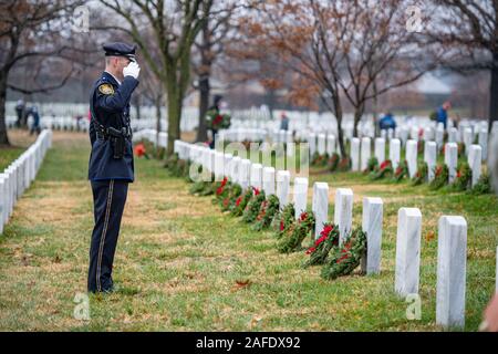 Arlington, Vereinigten Staaten von Amerika. 14. Dezember, 2019. Eine staatliche Polizei freiwillige begrüßt nach der Platzierung einen Kranz auf Grabstätten der Gefallenen service Mitglieder während der 28 Kränze über Amerika Tag auf dem Arlington National Cemetery Dezember 14, 2019 in Arlington, Virginia. Mehr als 38.000 Freiwilligen statt Kränze auf jeder Grabstätte auf dem Arlington National Cemetery und anderen Seiten rund um die Nation. Credit: Elizabeth Fraser/DOD/Alamy leben Nachrichten Stockfoto