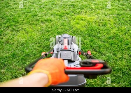 Die interessante Sicht von einem Mann treibt ein Rasenmäher. Rasenmäher Mähen von Gras. Stockfoto