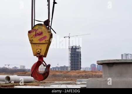 Große gelb-rot Kranhaken heben auf Ängste und Ketten Aufhängen zum Heben von Lasten auf einem Hintergrund Baustelle, resedental Gebäude- und Ausleger Stockfoto
