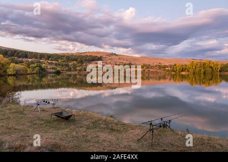 Karpfen angeln karpfen beißen Indikatoren und Rollen auf rod pod in der Nähe des Flusses. Angeln bei Sonnenaufgang. Stockfoto