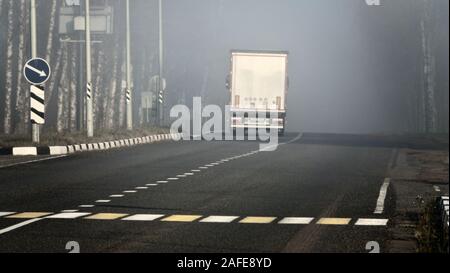 Lkw auf der Autobahn bei schlechtem Wetter mit dichtem Nebel. Natürliche Phänomene und Gefahren auf der Straße Stockfoto
