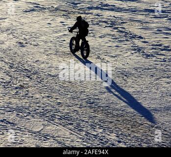 Radfahrer anonyme Silhouette auf einer fat Radtouren auf zugefrorenen Winter Meer am Strand. Stockfoto