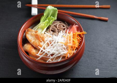 Teil der Soba Nudelsuppe mit Scheiben von Fried Chicken, Rettich, Karotten, Ingwer, mariniert und Blätter von Bok Choy Stockfoto