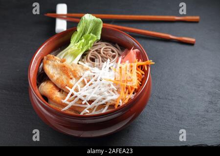 Teil der Soba Nudelsuppe mit Scheiben von Fried Chicken, Rettich, Karotten, Ingwer, mariniert und Blätter von Bok Choy Stockfoto