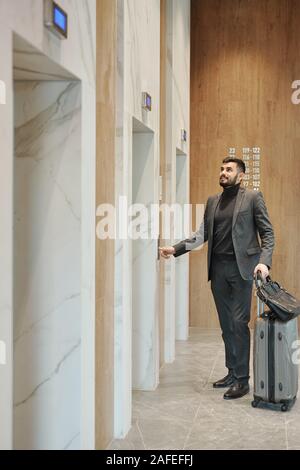 Geschäftsmann drücken Taste auf der Wand, während durch eine der Türen stehend Stockfoto