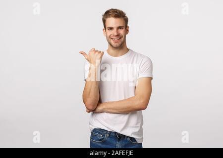 Sie sollten diese sehen. Sorglos, beiläufigen schönen blonden kaukasischen bärtigen Kerl, der Daumen links und lächelnd im Gespräch im Gespräch über die Firma Stockfoto