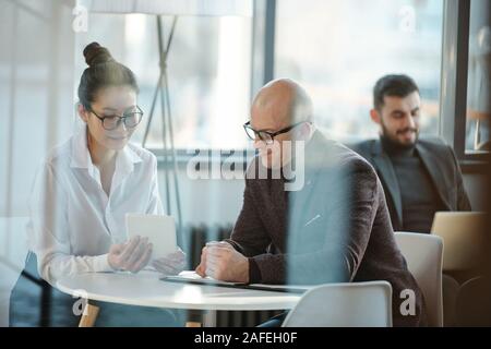 Asiatische Geschäftsfrau, die Präsentation zu reifen Kollege an Arbeitstreffen Stockfoto