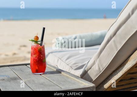 Glas Saft am Strand Tabelle im Sommer Tag. Stockfoto