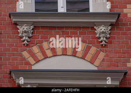 Eklektische Mietshaus arch Türen shell Lion's Head Relief alte Stein aus rotem Backstein detail Ornament Stockfoto