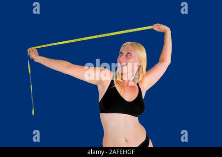 Junge Frau lacht an einem Maßband messen. Sie hat überwinden zwanghafter Analyse von Körper Bild Störungen wie Anorexia nervosa verursacht. Model Released Stockfoto