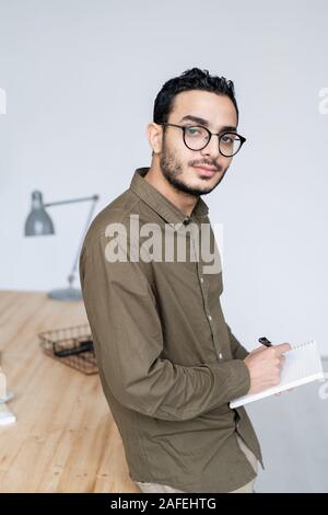 Junge Unternehmer in casualwear und Brillen zu Ihnen schauen, während Sie Notizen Stockfoto