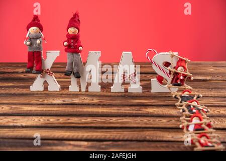 Holz- Buchstaben bilden Wort Weihnachten mit Bändern und roten Zahlen von Puppen neben Ihnen. die Puppe klettert die Strickleiter zu Buchstaben Stockfoto