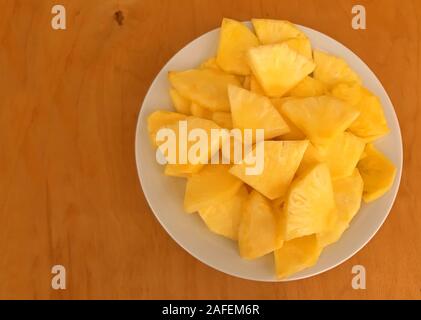 Ananas in Scheiben geschnitten in einer Platte, die auf einer hölzernen Hintergrund Stockfoto