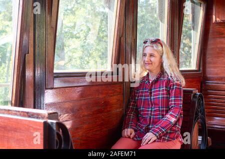 Frau gekleidet in einem royal Stewart tartan rot Shirt Vintage Zug sitzen - Sarganska 8. Stockfoto