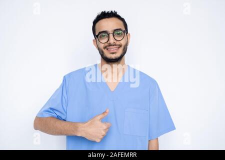 Junge erfolgreiche männlichen Chirurgen oder Arzt in der blauen Uniform mit Daumen hoch Stockfoto