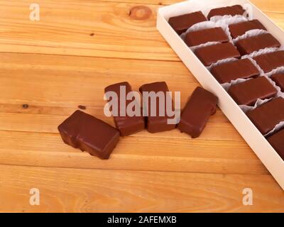 Verschiedene süße Pralinen in einer Box auf Holz- Hintergrund Stockfoto