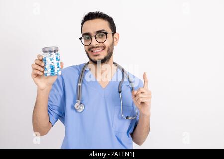 Junge zuversichtlich männlichen Kliniker mit Stethoskop und Pillen nach oben Stockfoto