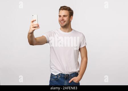 Käse sagen. Freundlich lächelnd schöne, stilvolle Blondine moderne Kerl mit Borsten, verlängern Hand, Smartphone, wobei selfie und lächelnd, Stream vlog Stockfoto