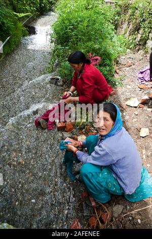 Manali, Indien, Himachal Pradesh: Zwei indische Frauen des Tibetischen Abstieg Kleidung waschen in einem Stream. Stockfoto