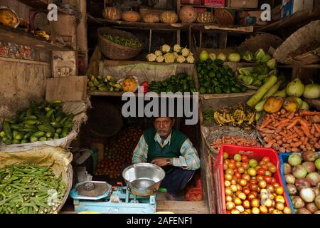 Manikaran, Himachal Pradesh, Indien: ein gemüsehändler unter Obst und Gemüse in seinem Geschäft Stockfoto