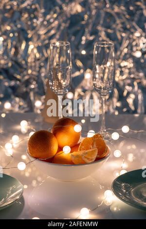 Weißes Porzellan Schale von Orangen mit Girlanden und zwei Flöten auf Tisch Stockfoto