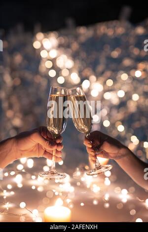 Die Hände der jungen Paar klirren mit Flöten Champagner auf Weihnachten Hintergrund Stockfoto