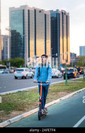 Mann mit elektrischer Roller für den Transport in einer modernen Stadt Umgebung Stockfoto