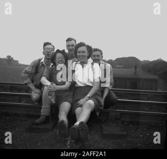 1950er Jahre, historisch, drei männliche und zwei weibliche Walker sitzen draußen für ein Foto auf einer Eisenbahnlinie, England, Großbritannien. Stockfoto