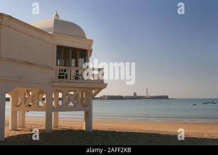 Detail von einem wunderschönen, alten Gebäude an der Playa de la Caleta in Cadiz, Spanien mit dem Castillo de San Sebastian und den Strand im Hintergrund Stockfoto