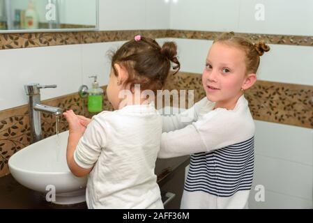 Zwei kleine Mädchen im Badezimmer Waschen der Hände. Niedlich süß Kinder spielen im Wasser. Gesunde, Kinder- und Hygienekonzept. Stockfoto