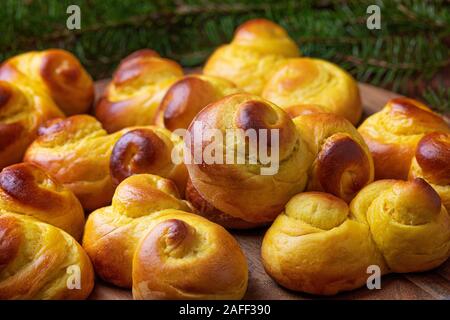 Schwedische traditionelle Weihnachten bun Lussekatter oder Lussebullar auf Holz- fach die Brötchen sind frisch und hausgemacht, und es gibt eine Defokussierten br Fichte Stockfoto