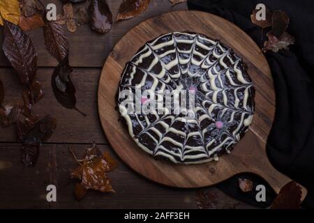 Halloween Spinnennetz Kuchen von klebrigen Schokolade Kuchen schwedische Kladdkaka, mit weißer und dunkler Schokolade dekoriert. Der Kuchen ist auf einem dunklen Holztisch, Stockfoto