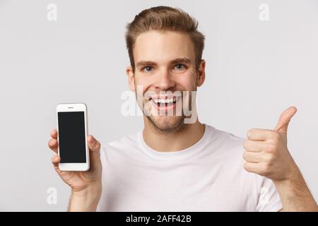 Schönes App, laden Sie es herunter. Aufgeregt und glücklich, blond kaukasischen Mann Anwendung empfehlen, Filter für Foto, Smartphone, Mobile zufrieden Stockfoto