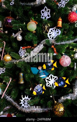 Nahaufnahme der Weihnachtsbaum mit Dekorationen - Beleuchtung, Christbaumkugeln, Lametta, Papier Schneeflocken, Zuckerstangen, Keramik Fisch, etc. Stockfoto