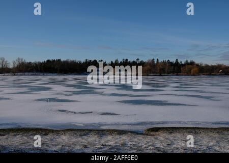 Helles Abstauben von Schneekanonen Muster auf einem zugefrorenen See mit einem Horizont von Bäumen in der Ferne - Dow's Lake, Ottawa, Ontario, Kanada. Stockfoto