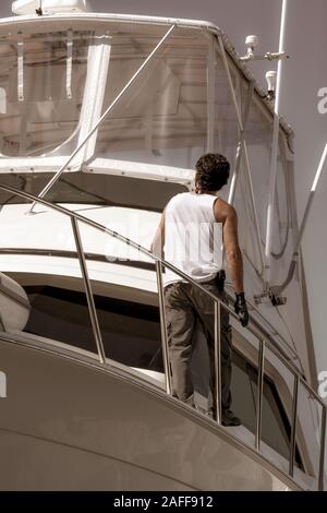 Eine Nahaufnahme, Ansicht von hinten von einem Mann zu Fuß entlang der Side Deck auf einem großen Boot mit seiner Hand am Geländer am Hafen in Santa Barbara, CA Stockfoto