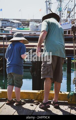 Ein Mann hilft ein Junge mit seiner Angelrute und Haspel von einem Steg in der Marina in den Hafen von Santa Barbara in Kalifornien gekleidet Stockfoto