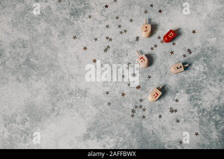 Chanukka Stoffzusammensetzung gestaltet. Dekorative Muster. Holz- Dreidel Spielzeug, goldenen und silbernen Konfetti Sterne Dekoration auf grunge konkreten Hintergrund. Stockfoto