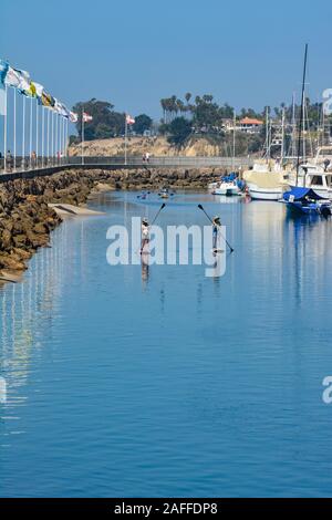 Zwei Frauen Manöver ihre Stand up Paddle Boards durch einen Kanal in der Nähe der Mole Pfad und Marina in den Hafen von Santa Barbara, Santa Barbara, CA, Stockfoto