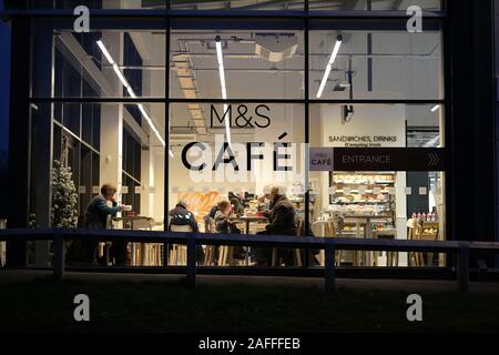 M&S Cafe mit Leute genießen Sie Ihre Mahlzeiten durch die Fenster in der Nacht gesehen. Stockfoto