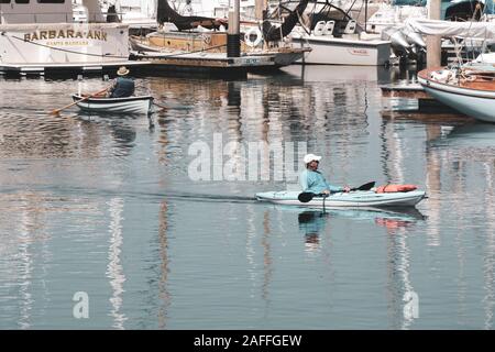 Ein Paddler und eine kanutin, Reisen in entgegengesetzte Richtungen an der Marina in den Hafen von Santa Barbara, Santa Barbara, CA Stockfoto