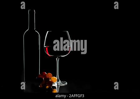 Elegante Rotwein Glas, Flasche Wein und Trauben auf dem dunklen Hintergrund. Valentinstag, Geburtstag Konzept. Stockfoto